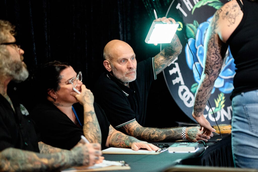 Tattoo artists discussing design at a convention.