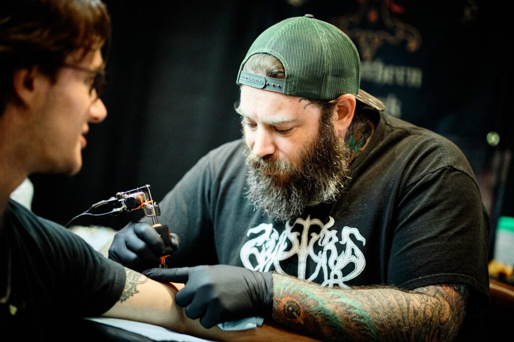 Tattoo artist working on client's arm tattoo