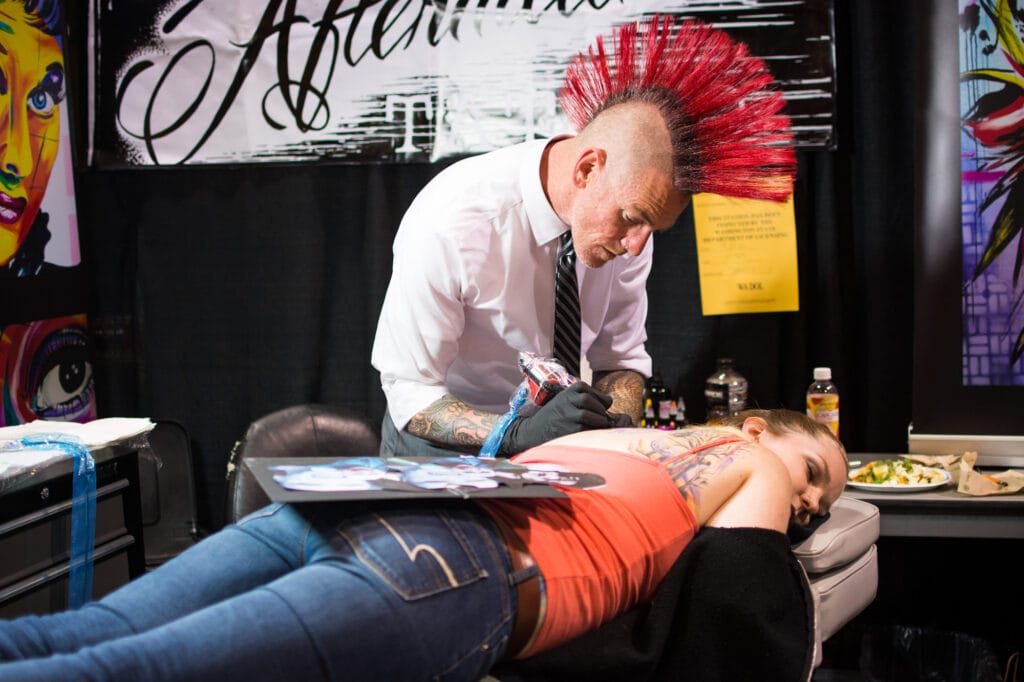 Tattoo artist inking woman's shoulder at studio.
