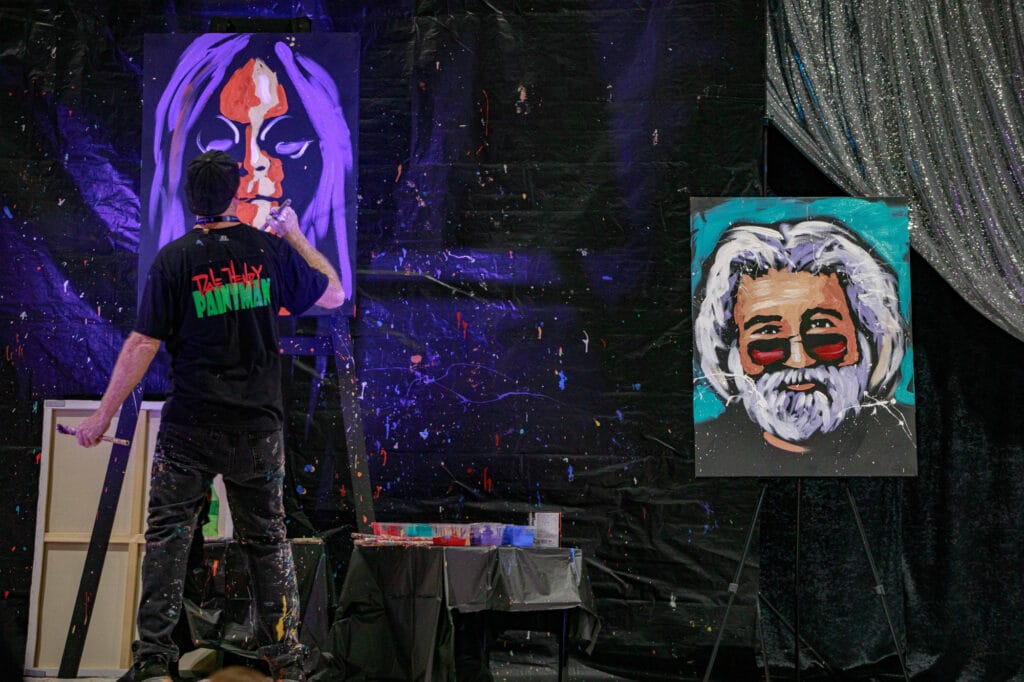 Artist painting vibrant portrait on canvas at event.