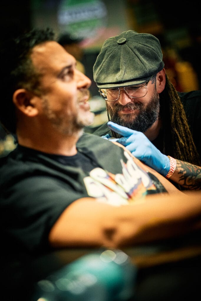 Tattoo artist working on client's arm.
