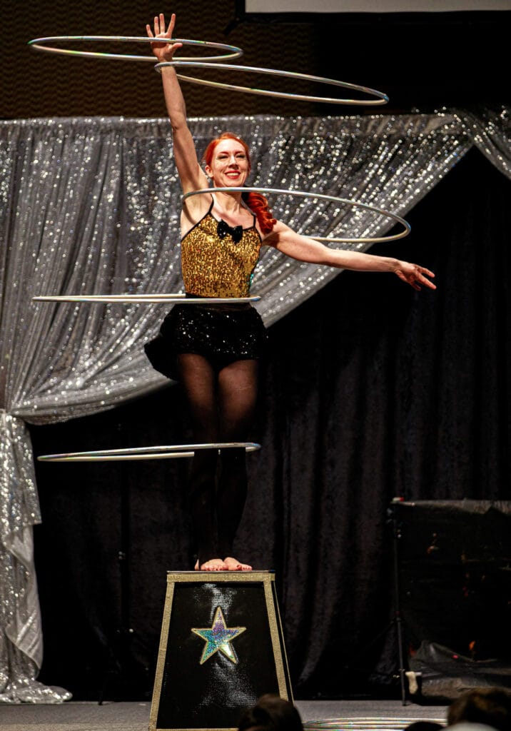 Performer balancing multiple hula hoops on stage.