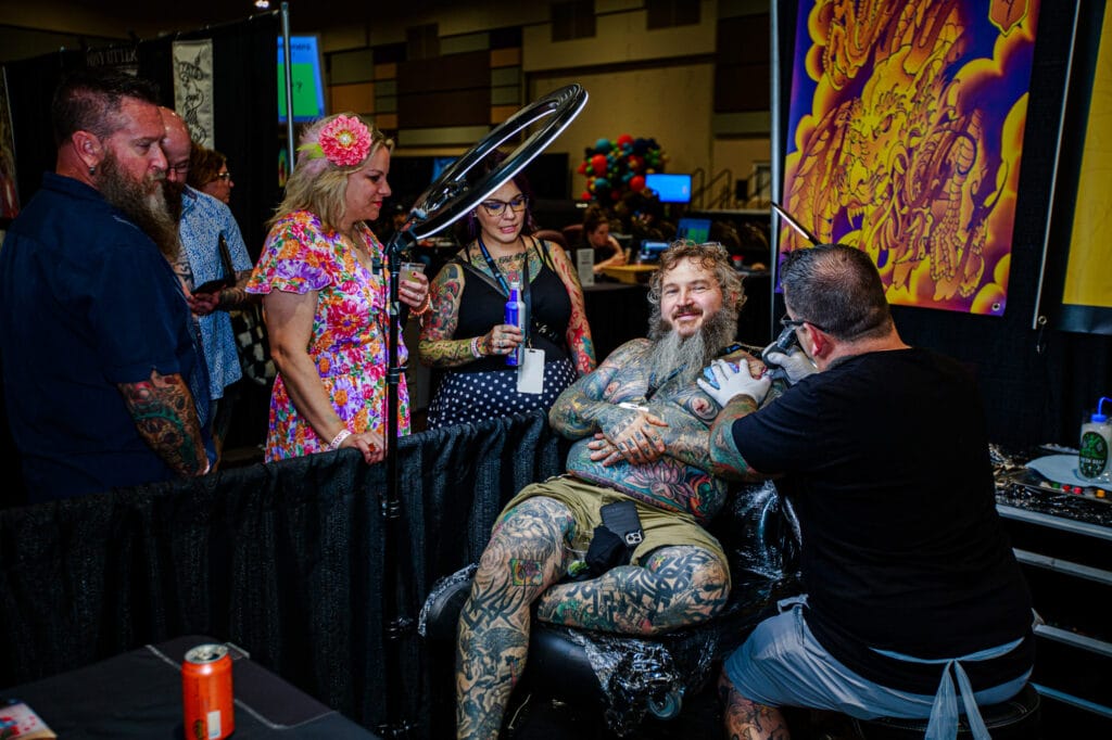 Tattoo artist working at a convention booth.