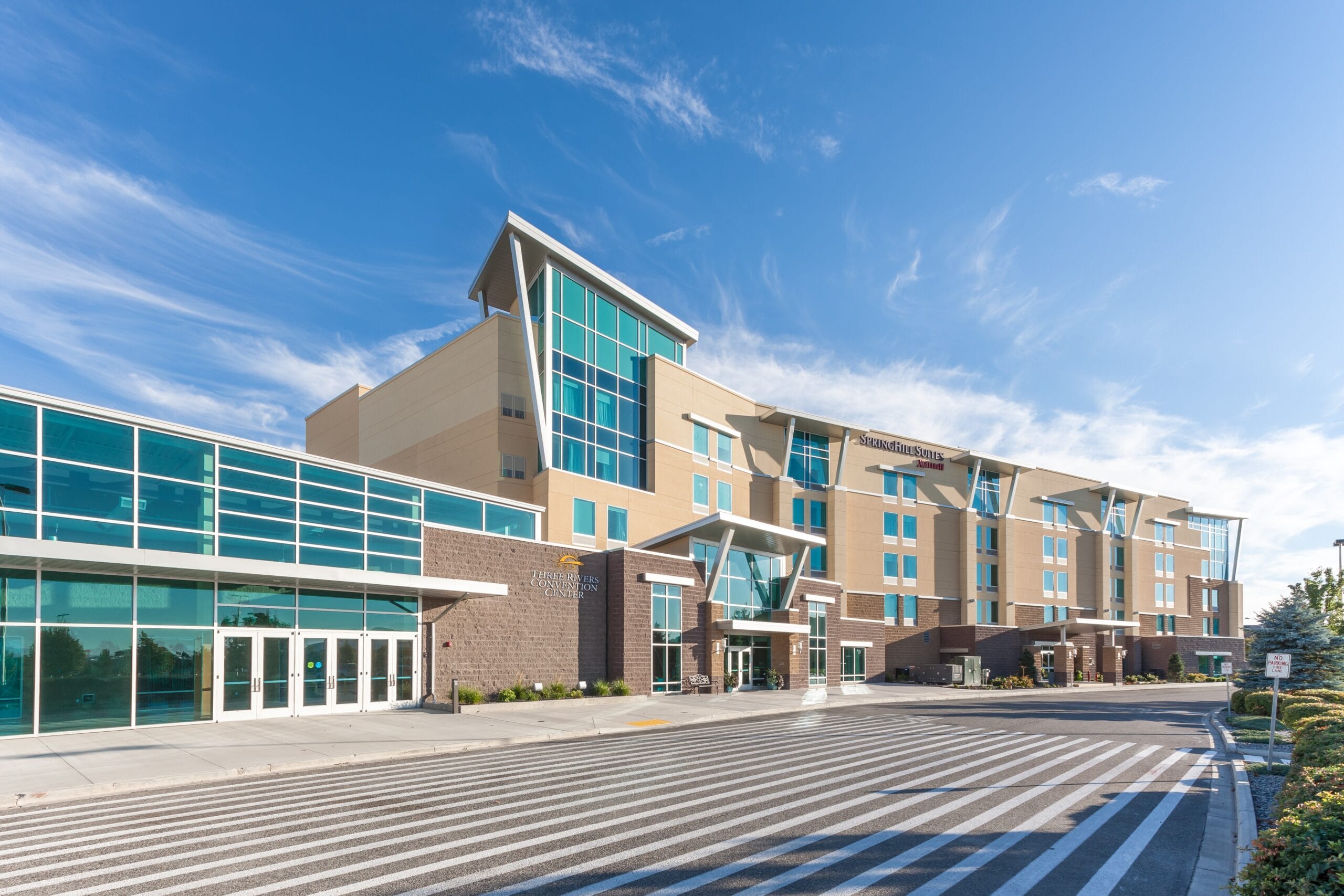 Modern hotel exterior with glass windows and blue sky.