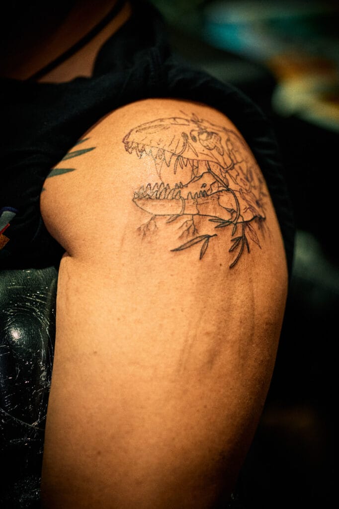 Dinosaur skull tattoo on upper arm.