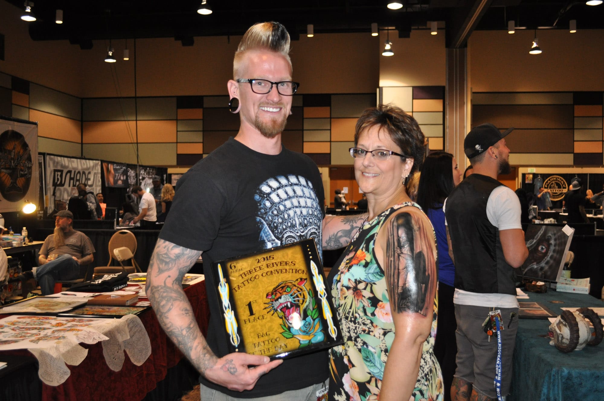 Winners at tattoo convention holding award.