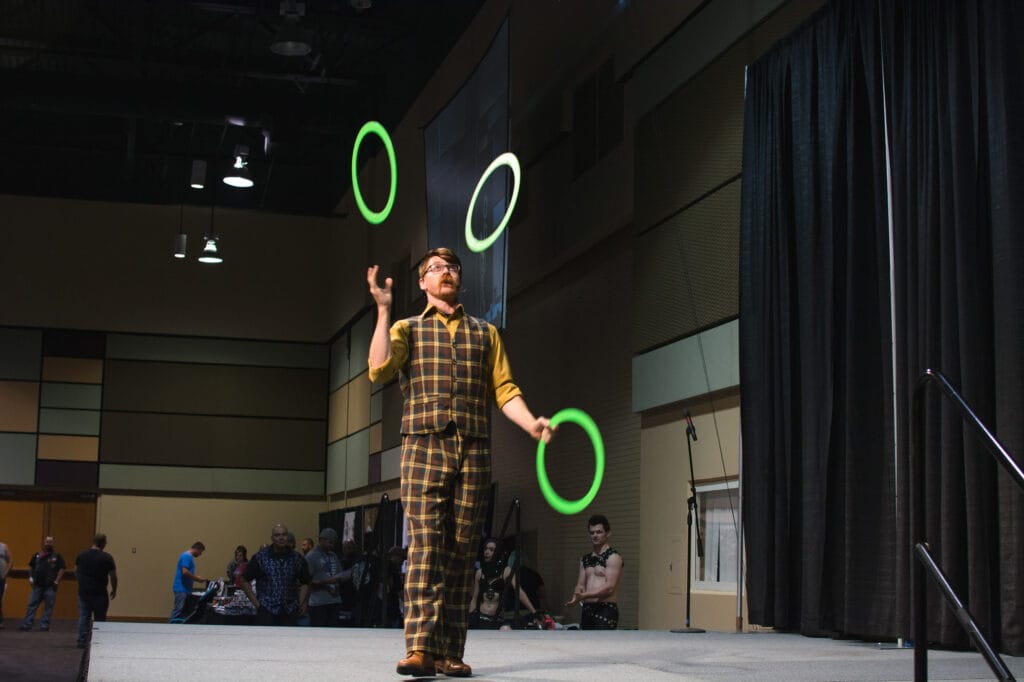Performer juggling green rings on stage.