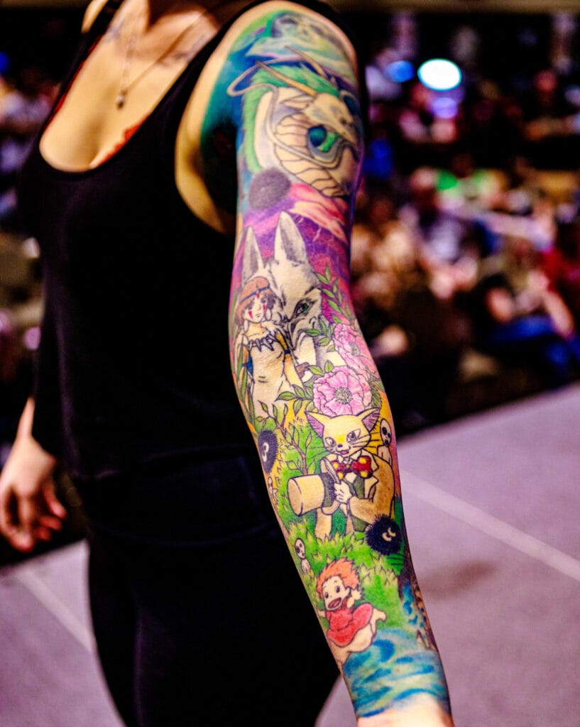 Colorful anime-themed sleeve tattoo on woman's arm.