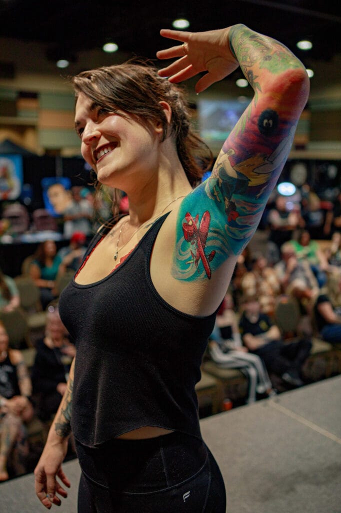 Woman showcasing colorful arm tattoo at event.