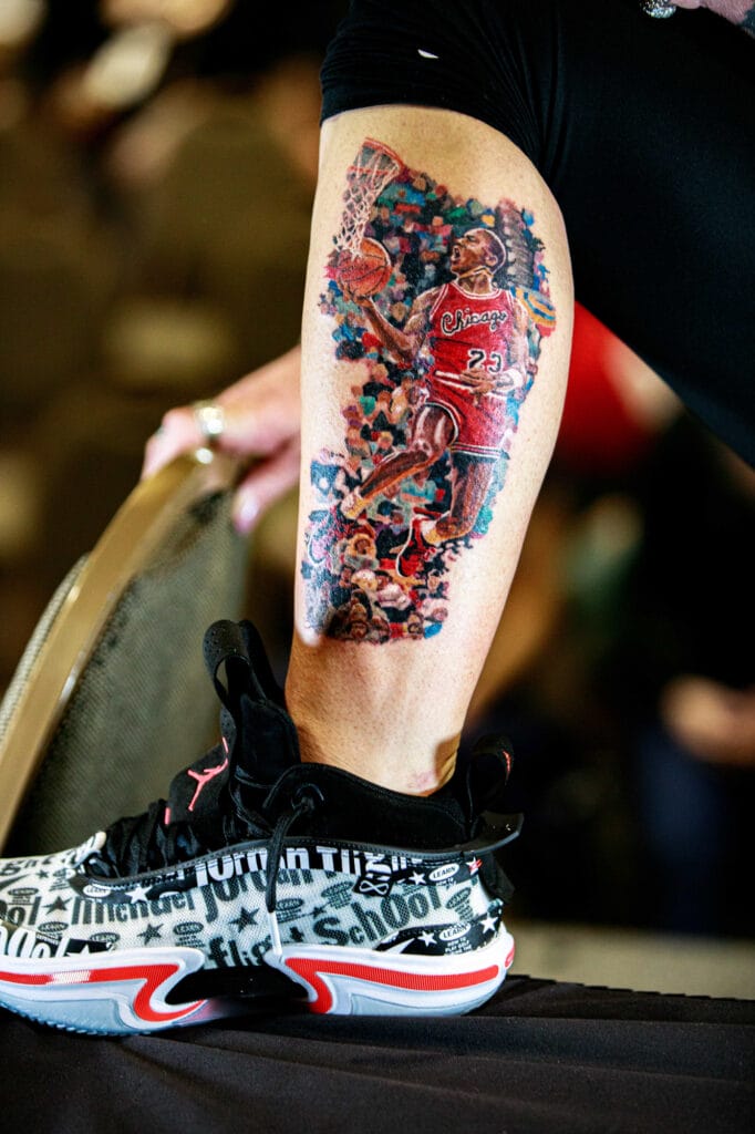 Leg tattoo of basketball player, colorful sneaker shoe.