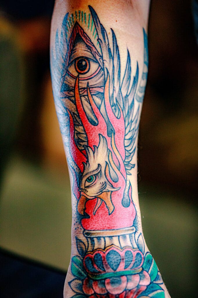 Colorful tattoo with eye and wings design.