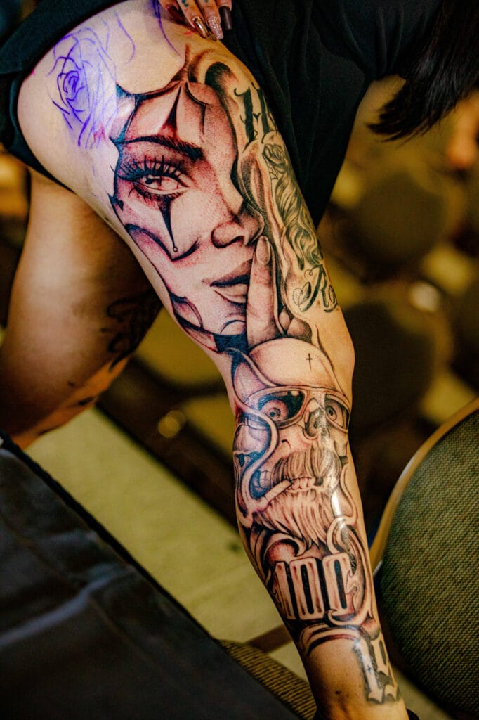 Detailed leg tattoos with faces and patterns.