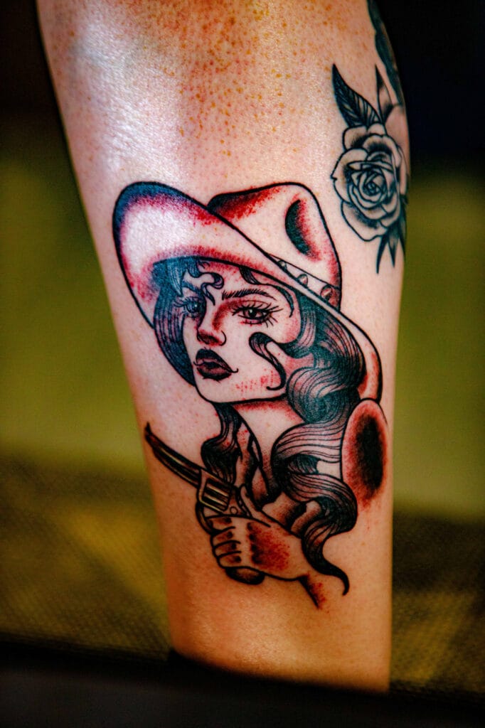 Cowgirl tattoo with rose and gun design