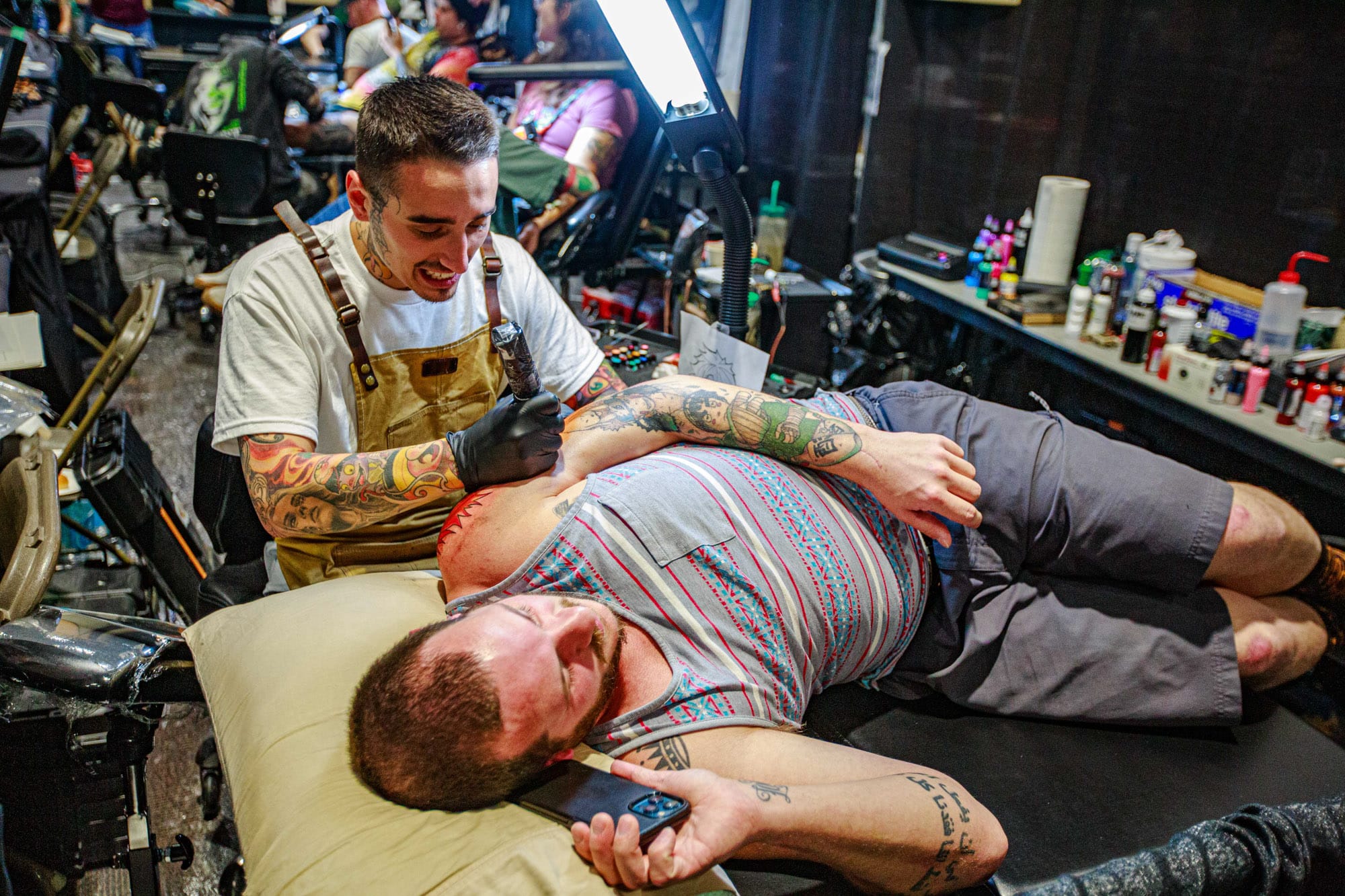 Tattoo artist working on client's arm tattoo.